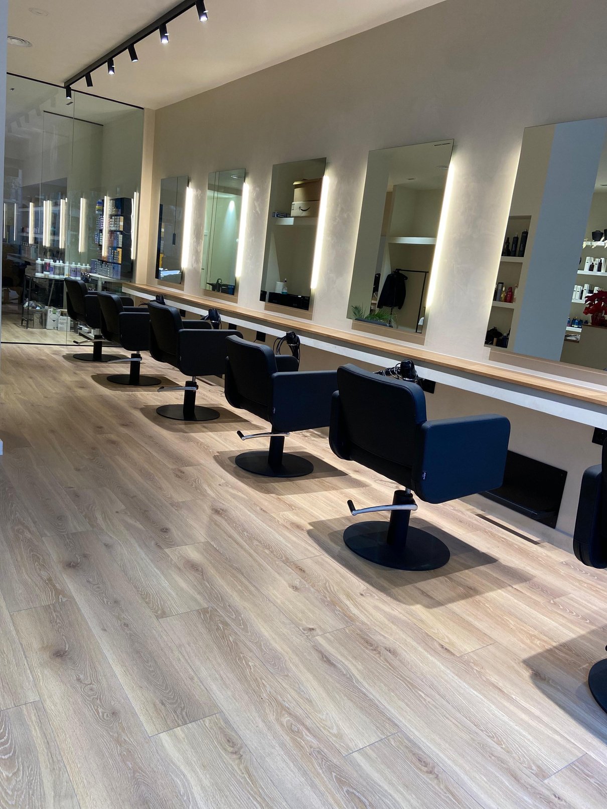 Zona de corte con sillones negros, espejos iluminados y conexión con el exterior