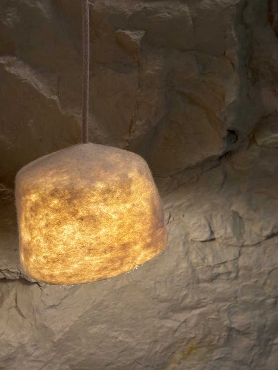 Luminaria de fieltro con luz cálida sobre la pared de piedra