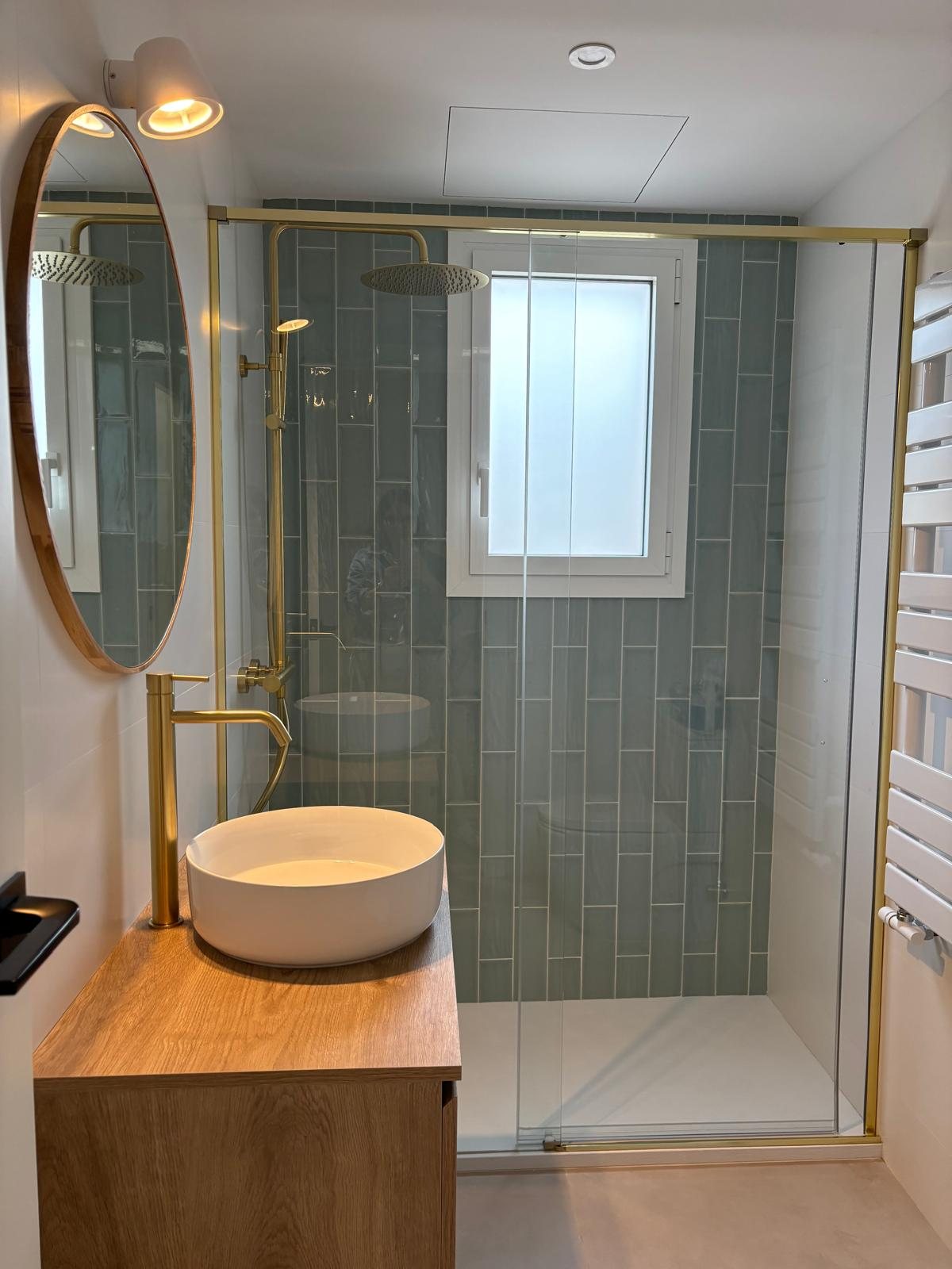 Baño luminoso de reforma integral con ventana, sanitarios blancos y acabados serenos