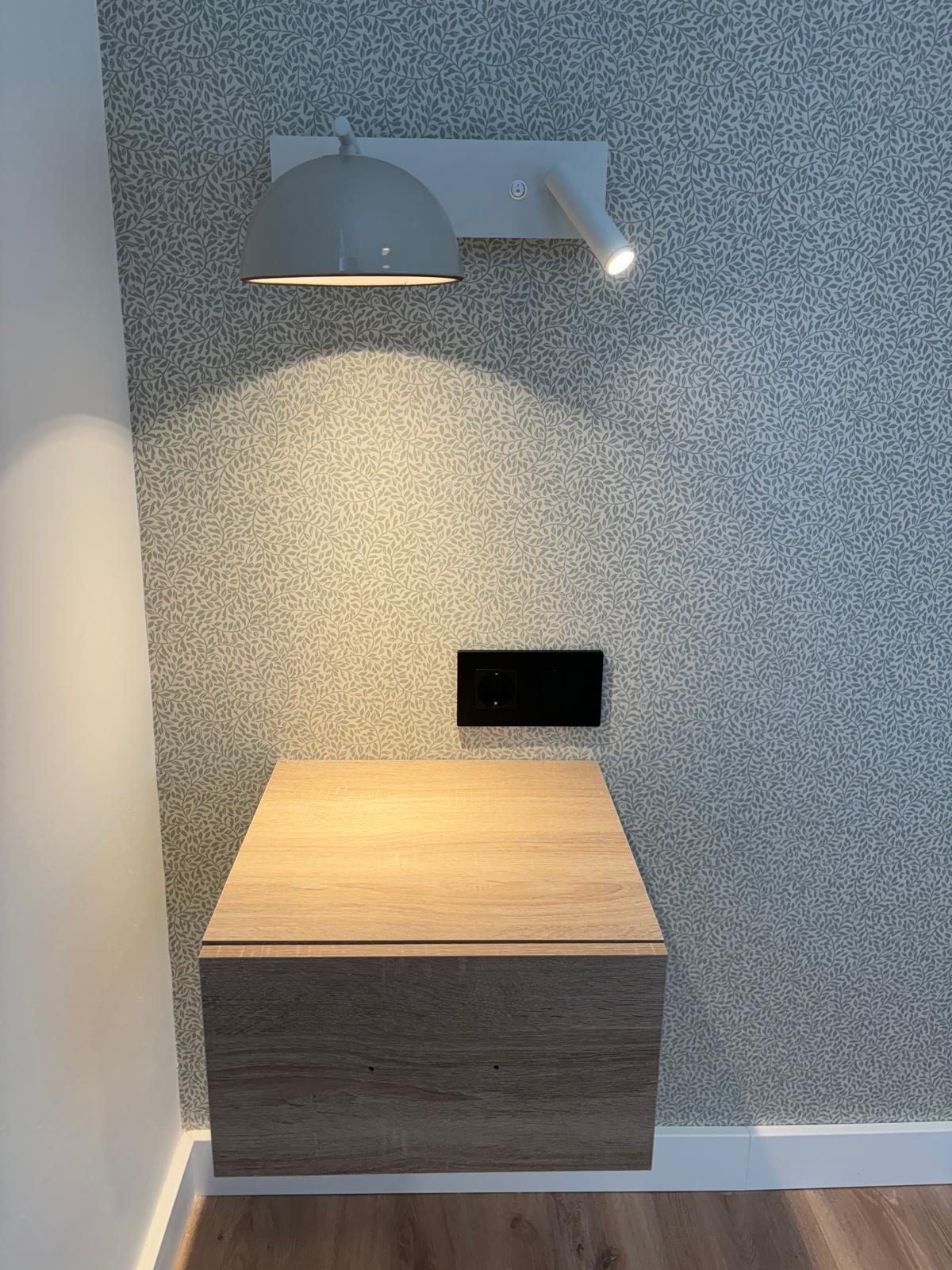 Papel pintado habitación con mesita de madera con aplique