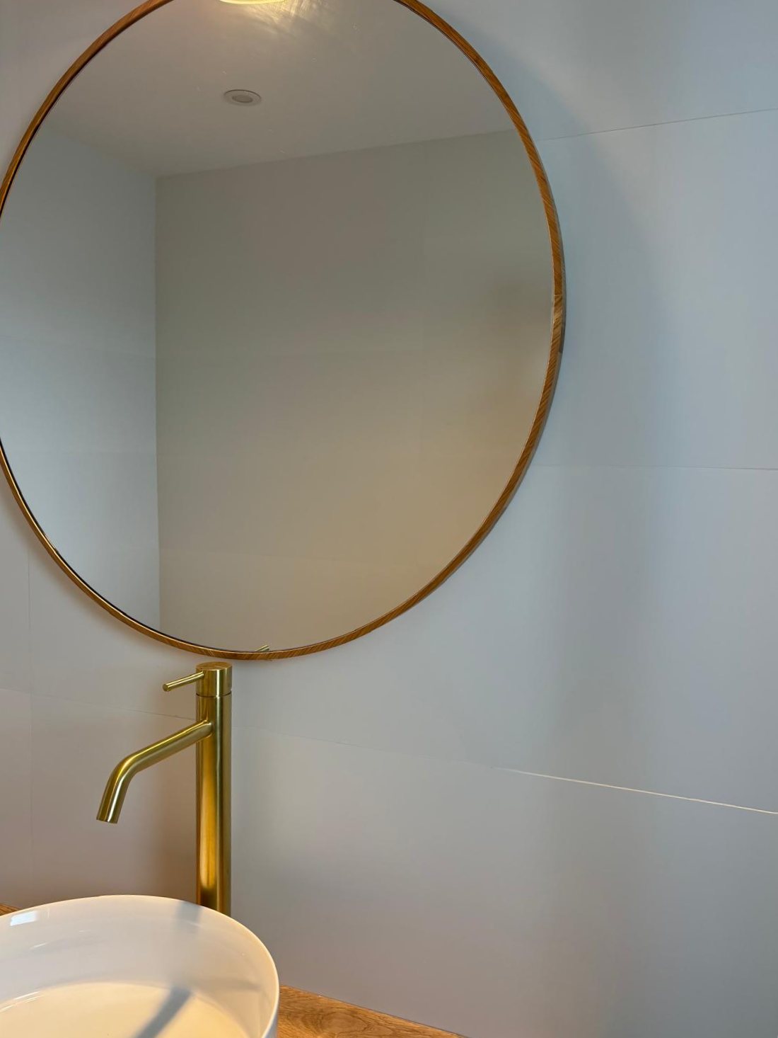 Lavabo con espejo redondo y grifería cuidada en vivienda reformada