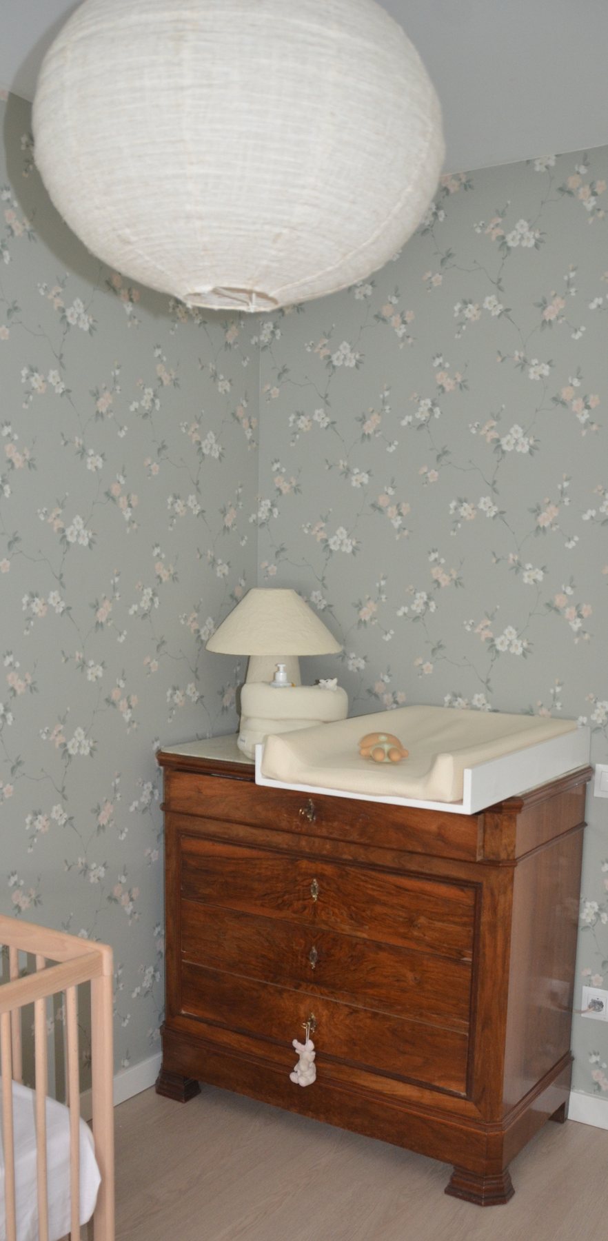 Dormitorio decorado con cómoda antigua, papel floral y piezas con historia